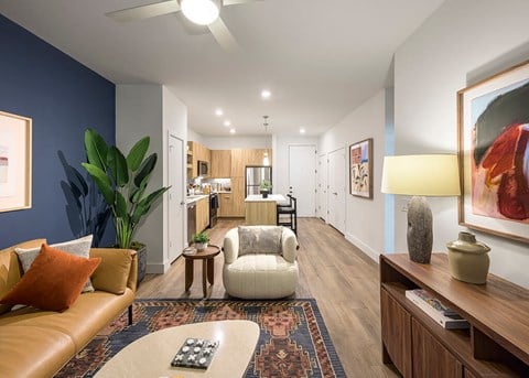 A living room with a brown leather couch, a white armchair, and a rug with a coffee table in the middle.